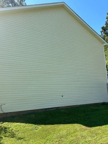 Side view of a house with light yellow siding and a clear blue sky in the background.